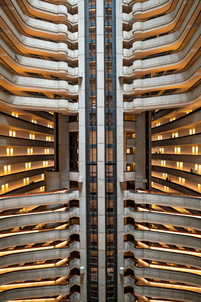 Curved stacked balconies of a hotel atrium, shot vertically in mirrored symmetry