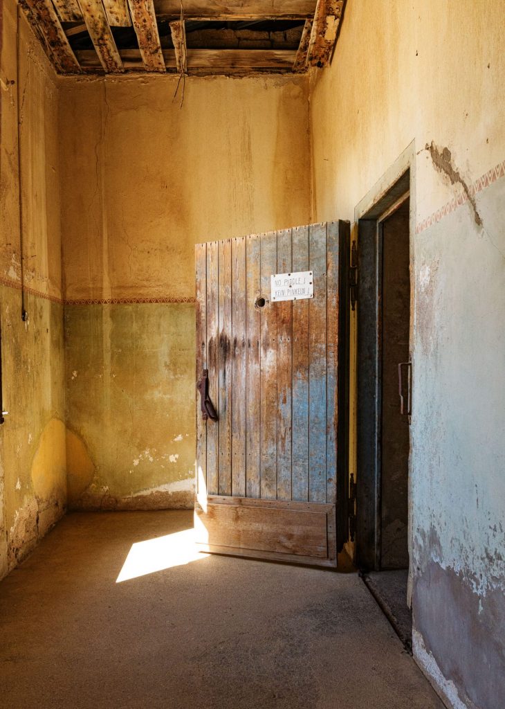 Room with ochre walls, a closed door and a notice fixed to it