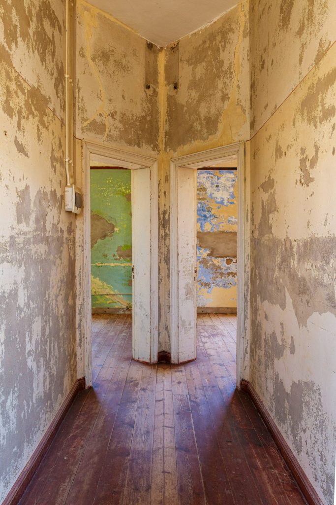 Narrow corridor framing a yellow door at its end, reddish wooden floor