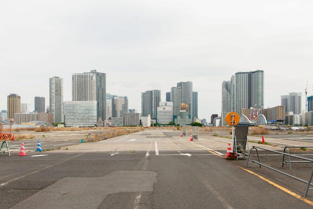Empty road with a distant skyline of high-rise towers and roadworks in the foreground