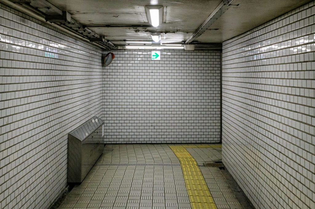 White tiled underground corridor with a yellow tactile guidance path on the floor