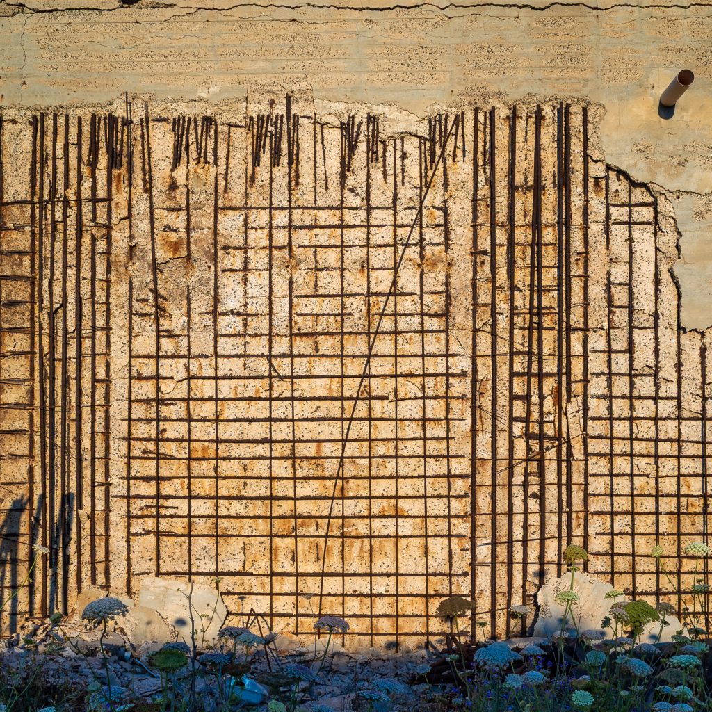 Concrete wall with vertical reinforcing bars and ochre streaks