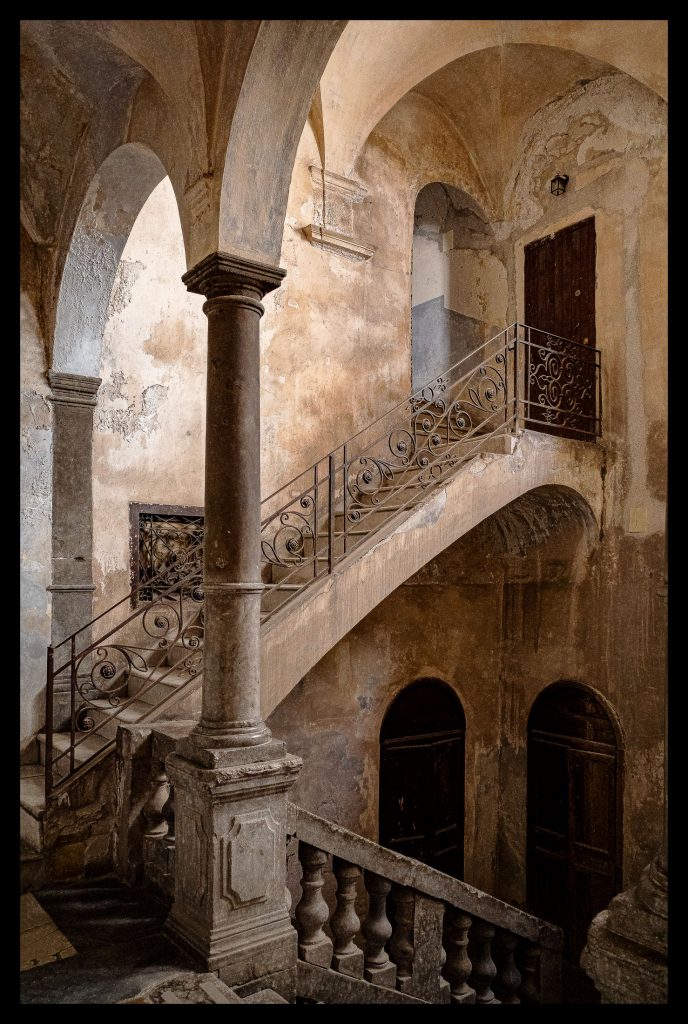 Baroque staircase with a stone column, tiered arches and a carved balustrade