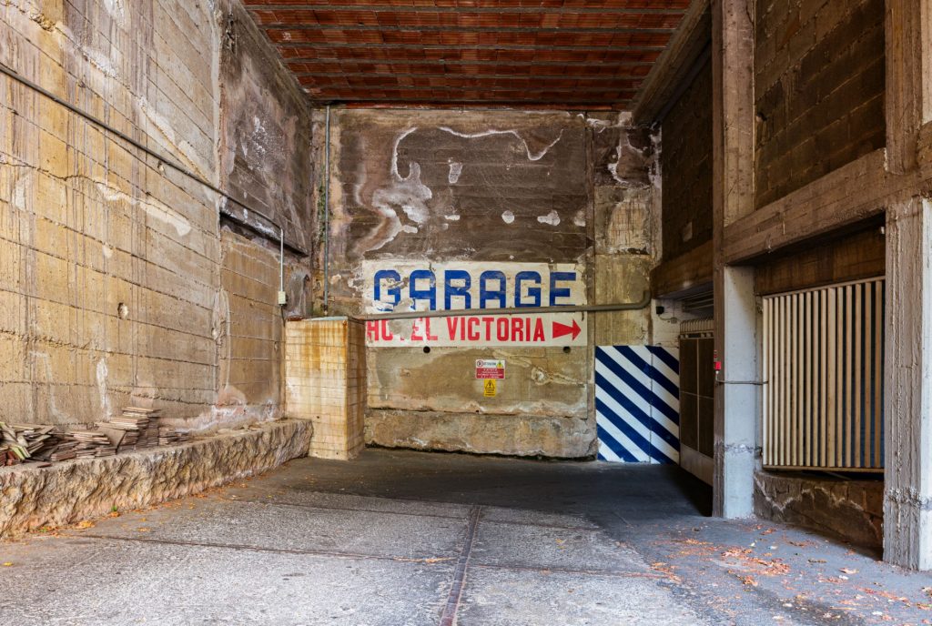 Garage with a GARAGE sign on the far wall and a white and blue striped barrier