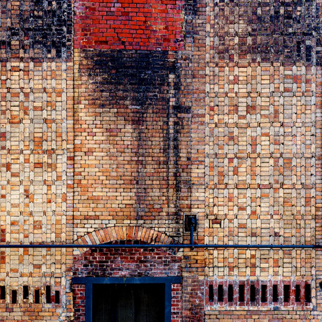 Wall of coloured brickwork forming a mosaic pattern in red and blue