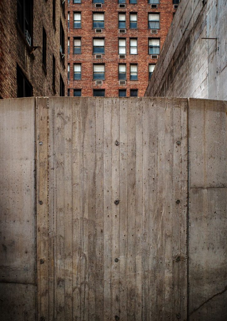 Concrete panels in the foreground with a brick building rising behind