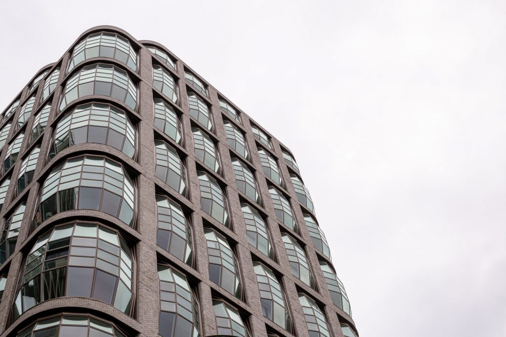 Building with a curved banded facade shot from below against a white sky