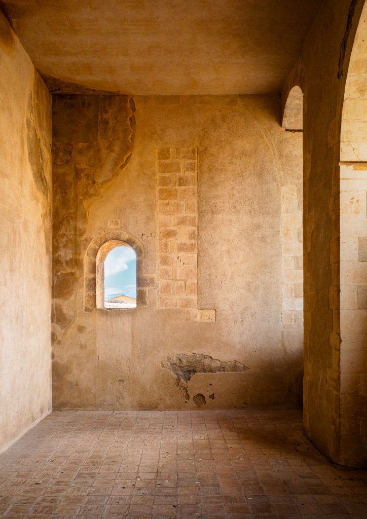 Vaulted room with ochre walls and a small arched window at the centre