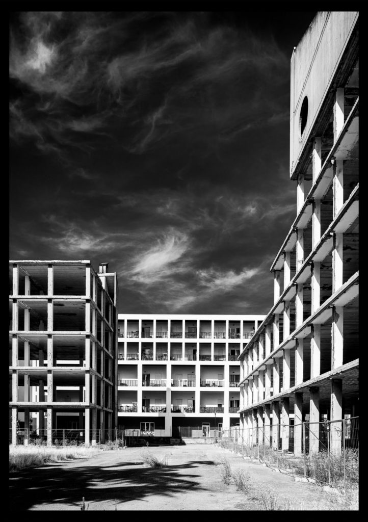 Modular concrete building in black and white beneath a sky of dark clouds